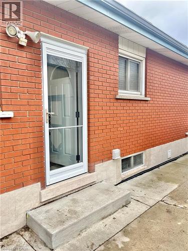 Exterior featuring red brickwork, a white storm door, and a concrete entrance step - 241 Thorner Drive, Hamilton, ON - Outdoor With Exterior