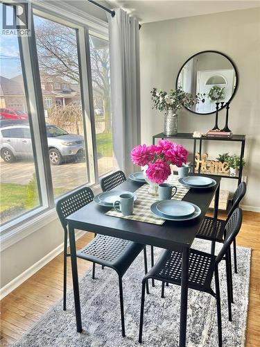 The dining area features large windows, hardwood floors, and a decorative mirror - 241 Thorner Drive, Hamilton, ON - Indoor