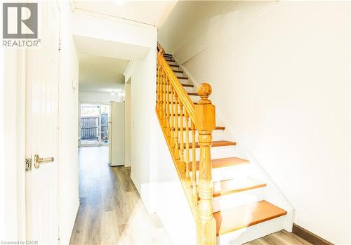 Entryway featuring a wooden staircase with a balustrade, light-colored walls, and wood-style flooring - 121 University Avenue E Unit# 102, Waterloo, ON - Indoor Photo Showing Other Room