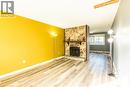 The living area features light wood-style flooring, a stone fireplace with a wooden mantel, and a bright yellow accent wall - 121 University Avenue E Unit# 102, Waterloo, ON  - Indoor With Fireplace 