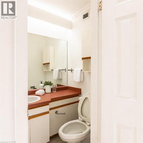 The bathroom features a vanity with a white sink, a terracotta-toned countertop, and white cabinetry - 121 University Avenue E Unit# 102, Waterloo, ON - Indoor Photo Showing Bathroom