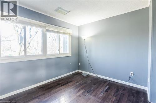 A room with dark hardwood flooring, light blue walls, and white trim - 121 University Avenue E Unit# 102, Waterloo, ON - Indoor Photo Showing Other Room