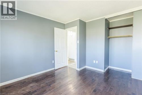 This room features dark hardwood flooring, light blue walls, and a white ceiling with crown molding - 121 University Avenue E Unit# 102, Waterloo, ON - Indoor Photo Showing Other Room