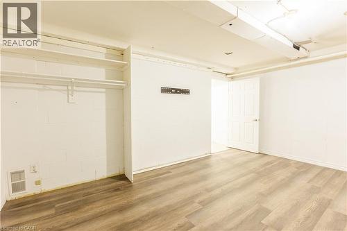 This room features light wood-look flooring, white walls, and a white paneled door - 121 University Avenue E Unit# 102, Waterloo, ON - Indoor Photo Showing Other Room