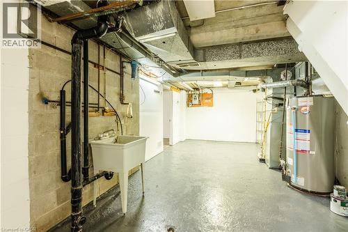 The property features a utility sink and a water heater, with exposed ductwork and piping - 121 University Avenue E Unit# 102, Waterloo, ON - Indoor Photo Showing Basement