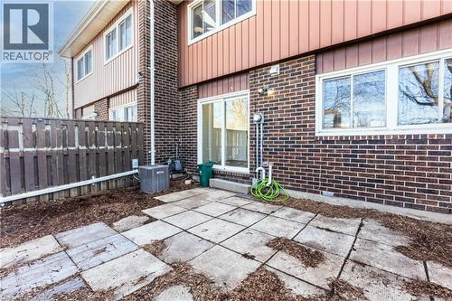 The property features a patio with square concrete pavers, a privacy fence, and a brick exterior with white-framed windows - 121 University Avenue E Unit# 102, Waterloo, ON - Outdoor