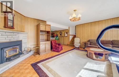 Living area featuring wood paneling, parquet flooring, a brick WOOD fireplace, and a hanging light fixture - 564 Glen Manor Boulevard, Waterloo, ON - Indoor With Fireplace