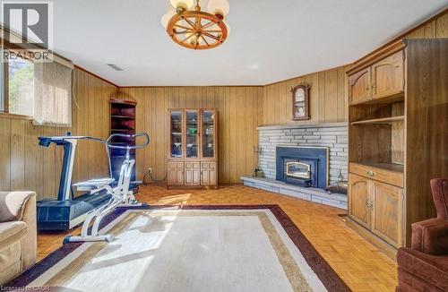 Living area featuring wood paneling, parquet flooring, a stone WOOD fireplace and a ceiling light fixture - 564 Glen Manor Boulevard, Waterloo, ON - Indoor With Fireplace