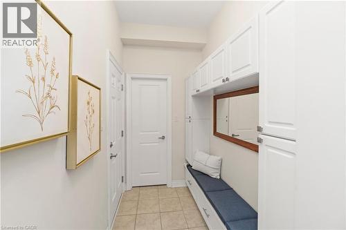 This entryway features white cabinetry, a built-in bench with a blue cushion, and a mirror with a wooden frame - 4 Macbean Crescent, Waterdown, ON - Indoor Photo Showing Other Room