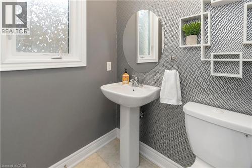 Bathroom featuring a pedestal sink, an oval mirror, and patterned wallpaper - 4 Macbean Crescent, Waterdown, ON - Indoor Photo Showing Bathroom