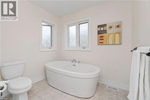 Spacious bathroom featuring a freestanding oval bathtub, a toilet, and two windows - 4 Macbean Crescent, Waterdown, ON - Indoor Photo Showing Bathroom
