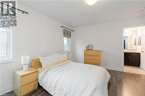 This room features two windows with patterned valances, light wood tone furnishings, and wood-style flooring - 4 Macbean Crescent, Waterdown, ON - Indoor Photo Showing Bedroom