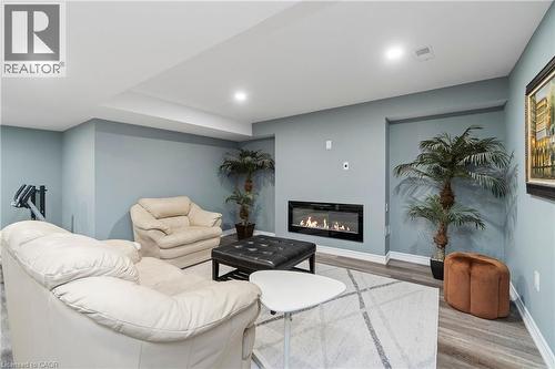 This inviting living area features an inset linear fireplace, recessed lighting, and light blue walls - 4 Macbean Crescent, Waterdown, ON - Indoor With Fireplace