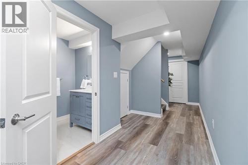This interior space features light blue walls, wood-style flooring, white trim, and a white interior door - 4 Macbean Crescent, Waterdown, ON - Indoor Photo Showing Other Room