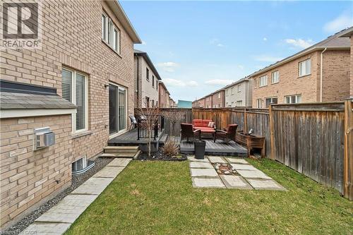 The property features an extensive backyard with a wooden deck, a lawn area, and a paved stone pathway - 4 Macbean Crescent, Waterdown, ON - Outdoor With Exterior