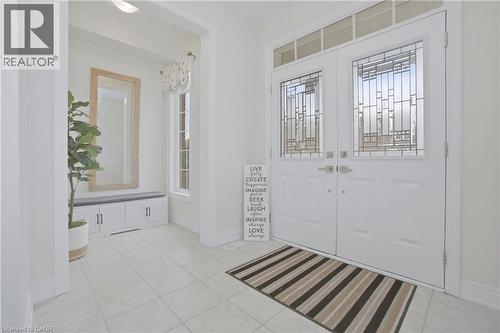 Inviting entry featuring a double front door with decorative glass inserts and an overhead transom window, tiled flooring, and a recessed area with a built-in bench and mirror - 4 Macbean Crescent, Waterdown, ON - Indoor Photo Showing Other Room