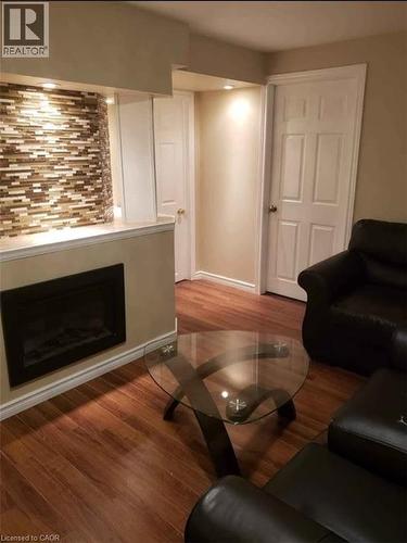 Living area featuring rich hardwood floors, an electric fireplace with a tiled accent wall, and recessed lighting - 679 Commonwealth Crescent Unit# Lower, Kitchener, ON - Indoor Photo Showing Living Room With Fireplace