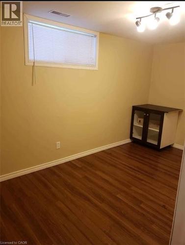 This room features rich brown flooring, a window with blinds, and track lighting - 679 Commonwealth Crescent Unit# Lower, Kitchener, ON - Indoor Photo Showing Other Room