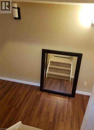 This space features hardwood flooring and wall-mounted lighting fixtures, creating a warm ambiance - 679 Commonwealth Crescent Unit# Lower, Kitchener, ON - Indoor Photo Showing Other Room