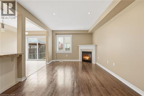 Unfurnished living room with a glass covered fireplace, dark wood finished floors, and recessed lighting - 91 Chamomile Drive, Hamilton, ON - Indoor With Fireplace