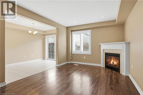 Unfurnished living room featuring wood finished floors, a high end fireplace, and suspended lighting - 91 Chamomile Drive, Hamilton, ON - Indoor Photo Showing Living Room With Fireplace