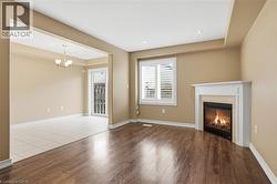 Unfurnished living room featuring wood finished floors, a high end fireplace, and suspended lighting - 