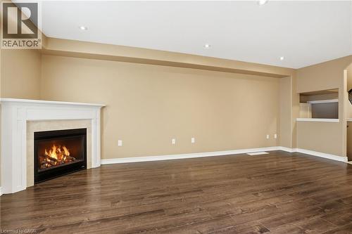 Unfurnished living room featuring dark wood-style flooring, recessed lighting, and a fireplace - 91 Chamomile Drive, Hamilton, ON - Indoor With Fireplace