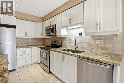 Kitchen with stainless steel appliances, white cabinetry, light stone countertops, light tile patterned floors, and recessed lighting - 91 Chamomile Drive, Hamilton, ON - Indoor Photo Showing Kitchen With Stainless Steel Kitchen With Double Sink With Upgraded Kitchen