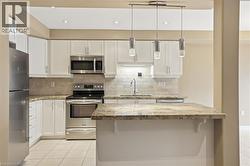 Kitchen with stainless steel appliances, white cabinets, and light stone countertops - 