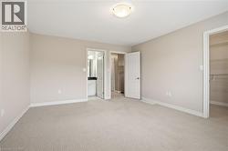 Master bedroom featuring a walk in closet and light colored carpet - 