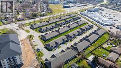 Aerial view showcasing a community of properties featuring grey roofs and private driveways, surrounded by green lawns and mature trees - 
