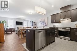 The open concept living area features a kitchen with dark cabinetry, granite countertops, and stainless steel appliances, including a dishwasher and stove - 