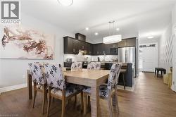 Open-concept living space featuring hardwood floors, dark wood kitchen cabinetry, a kitchen island with seating, and a white front door with sidelight window - 