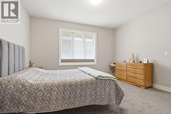 Bedroom with neutral-toned walls, carpeted flooring, and a window featuring blinds - 