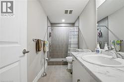 Bathroom featuring a white vanity with a marble-look countertop and an integrated sink, a tiled shower with a shower curtain, and light gray wall tiles - 