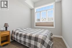 This room features a window providing natural light, light gray walls, and carpeted flooring - 