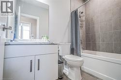Bathroom featuring a white vanity with a marble-patterned countertop, a rectangular mirror, and a combination bathtub and shower with grey wall tiling - 