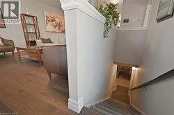 Living area featuring hardwood flooring and a staircase with a handrail and carpeted steps - 