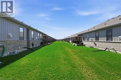 The property features a well-maintained green lawn, bordered by stone and siding exterior walls - 