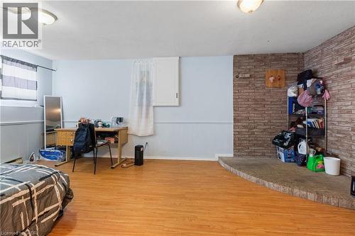 Bedroom featuring a wainscoted wall, light wood-type flooring, brick wall, a desk, and a textured ceiling - 23 Amherst Drive, Kitchener, ON - Indoor Photo Showing Other Room