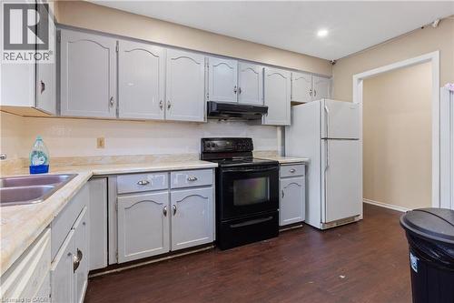 Kitchen featuring white appliances, light countertops, dark wood-style floors, and gray cabinetry - 23 Amherst Drive, Kitchener, ON - Indoor Photo Showing Kitchen With Double Sink