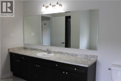 Vanity area featuring a long dark wood-finish cabinet with silver-tone hardware, a light-toned countertop, and an integrated white porcelain sink - 40 Compass Trail, Cambridge, ON - Indoor Photo Showing Bathroom