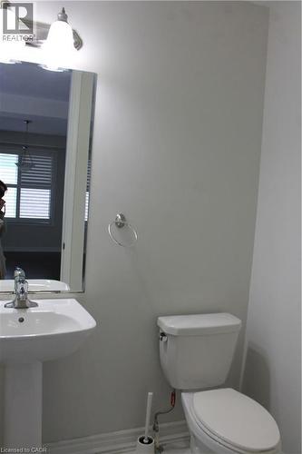 Pedestal sink with chrome faucet, mirror, and two-light vanity fixture - 40 Compass Trail, Cambridge, ON - Indoor Photo Showing Bathroom