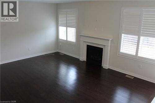 Living area featuring dark wood-finish flooring, light-toned walls, and white plantation shutters - 40 Compass Trail, Cambridge, ON - Indoor With Fireplace