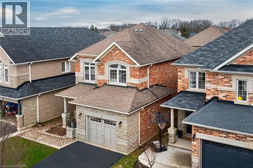 The property features a brick and stone facade, an attached garage, and a paved driveway - 44 Matteo Trail, Hamilton, ON - Outdoor