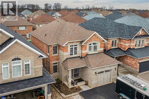 This property features a two-story design with a brick and stone facade, a covered front porch, and an attached garage - 44 Matteo Trail, Hamilton, ON - Outdoor