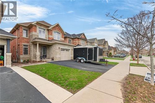 The property features a brick and stone facade, a paved driveway, and an attached garage - 44 Matteo Trail, Hamilton, ON - Outdoor With Facade