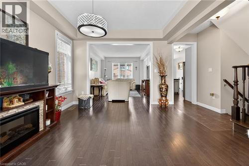 The property features dark hardwood flooring throughout, a decorative light fixture, and an open concept layout providing clear sightlines to other areas - 44 Matteo Trail, Hamilton, ON - Indoor Photo Showing Living Room With Fireplace