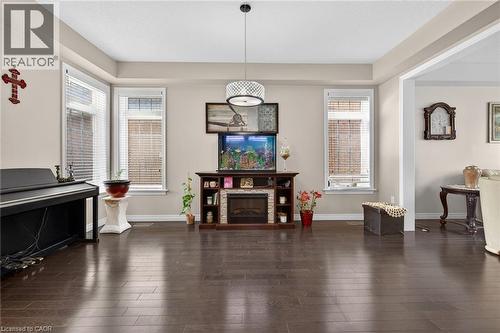 The living area features dark hardwood flooring, light-colored walls, and large windows with blinds - 44 Matteo Trail, Hamilton, ON - Indoor Photo Showing Other Room