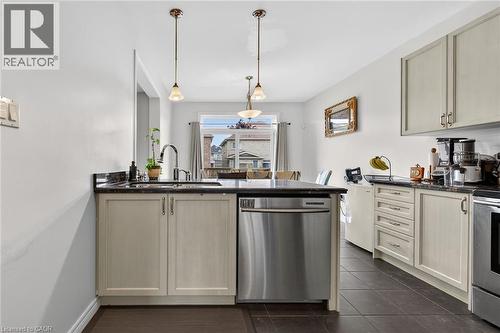 The kitchen features light-colored cabinetry, dark countertops, a stainless steel dishwasher, and tile flooring - 44 Matteo Trail, Hamilton, ON - Indoor Photo Showing Kitchen With Upgraded Kitchen